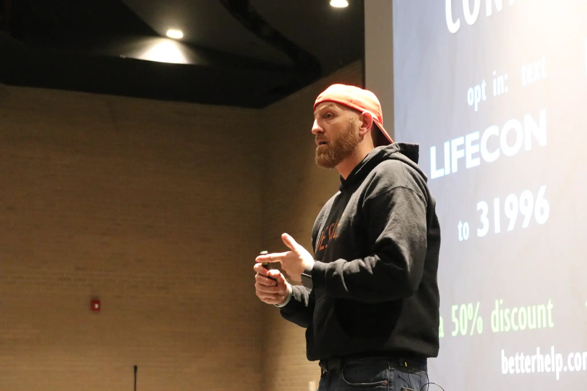 Ethan Fisher speaking at UNLV, wearing a backwards cap